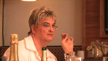 a woman in glasses looking bored while having a drink