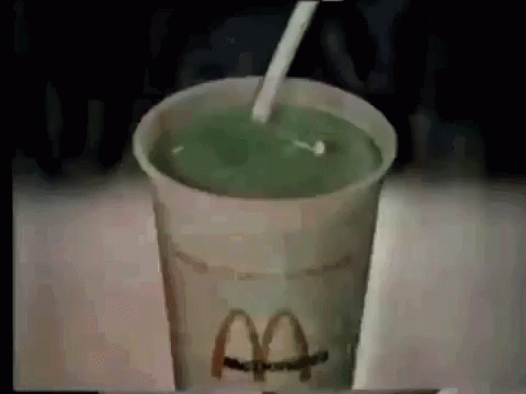 a picture of an iced green drink with a paper straw