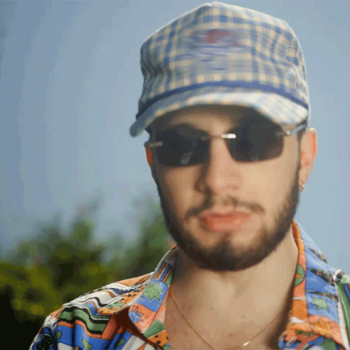 a man wearing a plaid cap while making a face