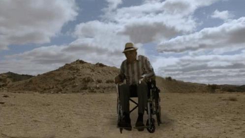 the man is sitting on a chair in the desert