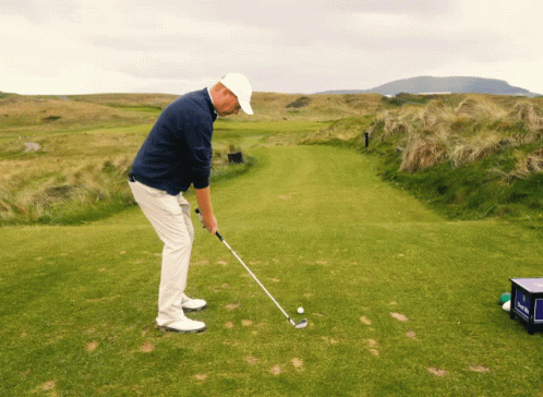 a man in brown shirt and white pants playing golf