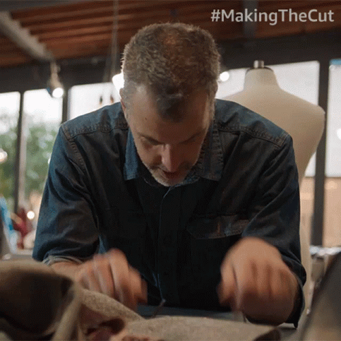 a man looks down as he cuts fabric