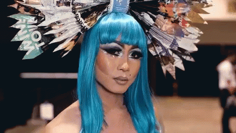 a woman with blonde hair and blue make up is wearing paper decorations