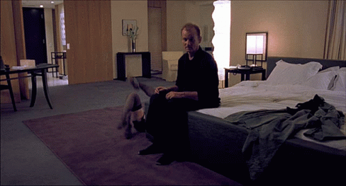 a man sitting on a bed in a blue bedroom