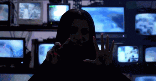 a woman making the hand gesture in front of tvs
