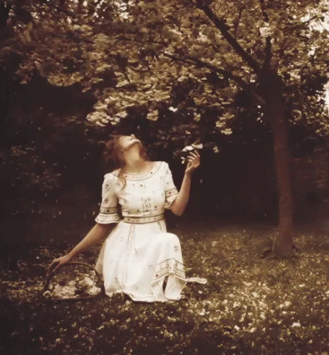 a woman sitting in the grass under a tree