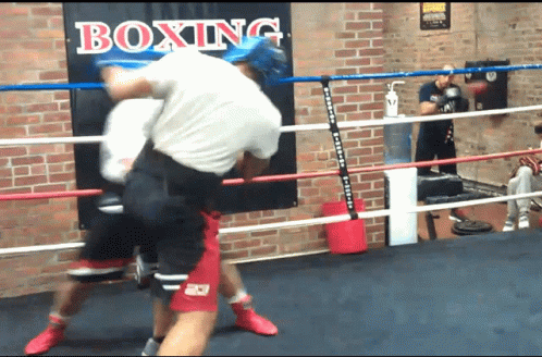 a man is standing near the ring and punching another person