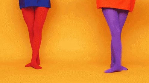 two women are in brightly colored outfits, one wearing heels