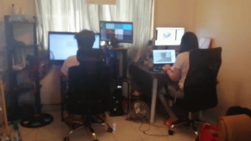 people sitting in a room with computers and monitors