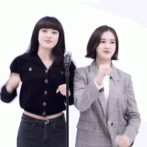 two young ladies, one singing into a microphone