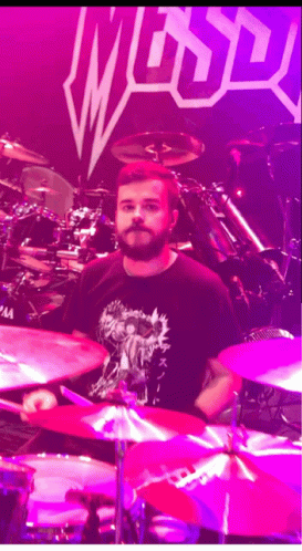 drummer playing drums on stage in front of purple background
