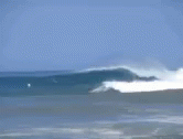 two surfers in the ocean while one is riding a wave