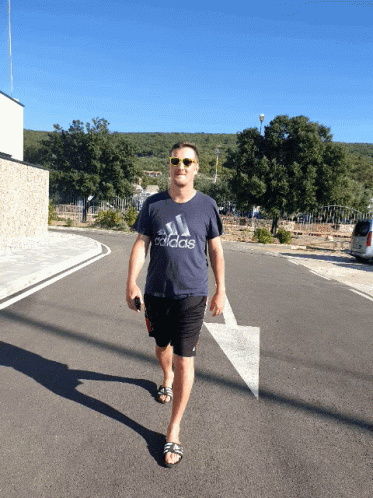 man wearing sunglasses walks along an empty street