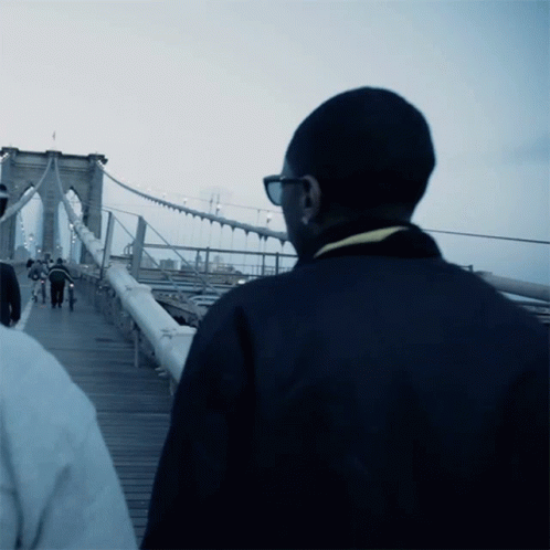 two men standing next to each other on a bridge