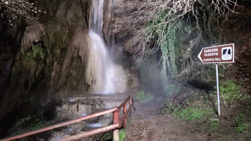 a couple of stairs and a sign in front of a waterfall