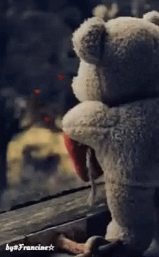 teddy bear with back turned sitting on porch rail