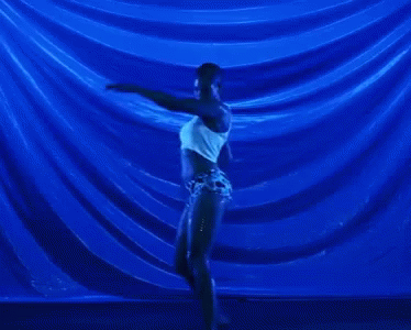 a dancer in front of red curtains performing