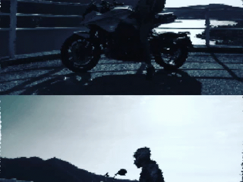 the man is standing beside his motorcycle and looking back