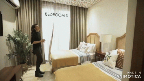 a woman is standing by a bed in a bedroom