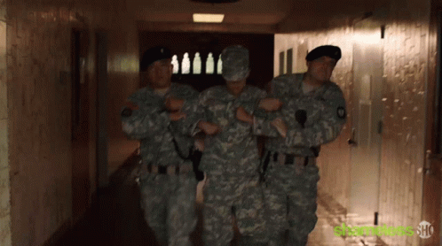 some soldiers walking down a hallway towards the door