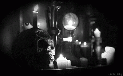 an ghostly woman sits next to candles, in the dark