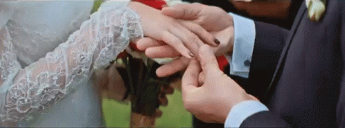 a couple dressed in wedding attire and one is adjusting the hand of a bride who is putting on a flower