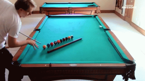 a man is looking at a table with pool balls