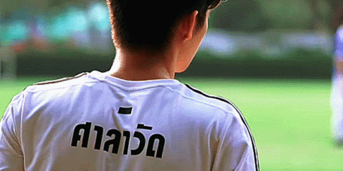 a boy is wearing a uniform and standing in front of a soccer field