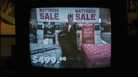 a bed in front of a tv showing mattress sale