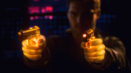 a man holding a gun at night while pointing the guns
