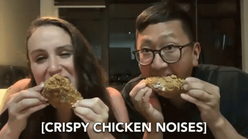 a man and woman sharing a bite of chicken nuss