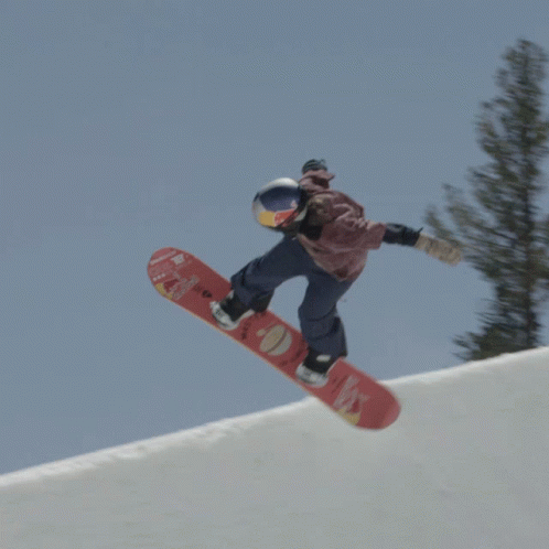 a snowboarder in a blue jacket does a trick in the air