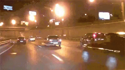 several cars driving down a rainy night in a lot