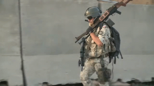 a soldier is carrying a weapons on his shoulder and the other gun in hand