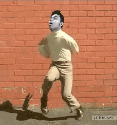 a man walking on concrete in front of a blue brick wall