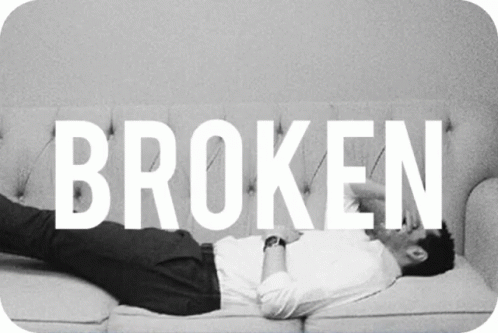 a man is lying on a couch holding the word broken