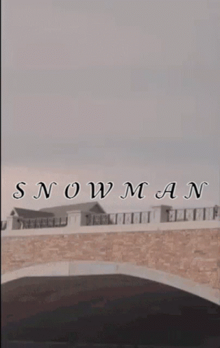 a snowman is standing on a bridge in front of a building