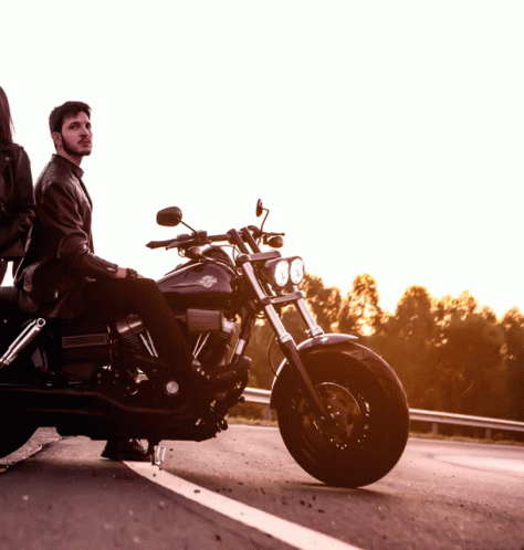man sitting on motorcycle standing in front of another motorcycle