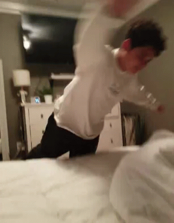 a blurry man on the edge of a bed stretching and jumping over