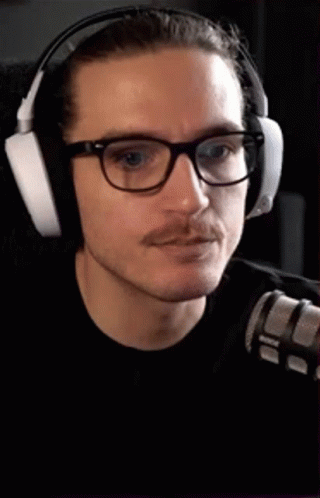 the man with glasses wears headphones and is looking at the camera