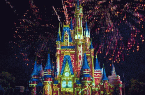 fireworks at the side of a brightly lit castle with towers