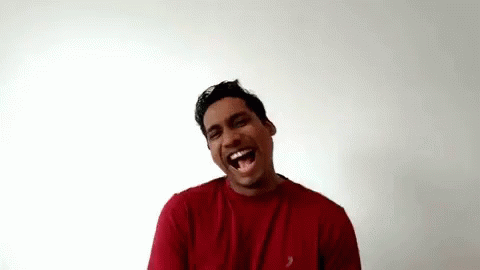 a man standing in front of a white wall laughing