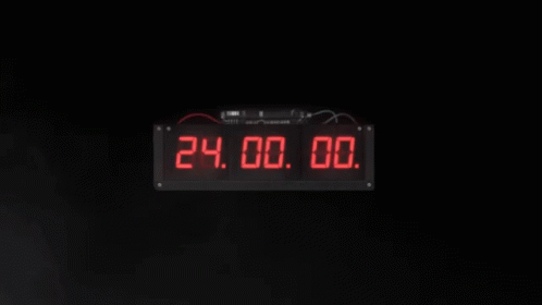 a black clock with blue numbers is shown in the dark