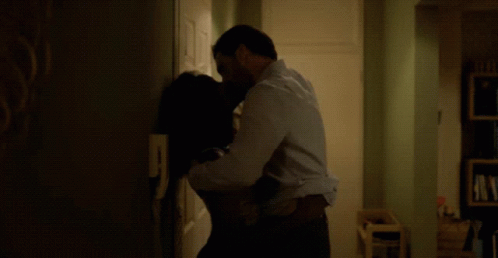 a man and a woman in a dark room hug while one person takes his picture