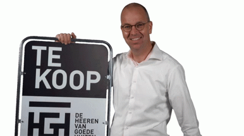 the man smiles next to a sign that says it's a koop