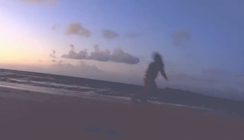 a blurry image of a person walking on the beach near the ocean