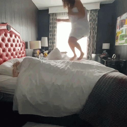 a person jumping on top of sheets in a el room