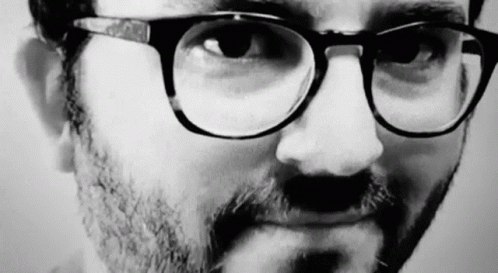 a man in glasses with his nose close up to the camera
