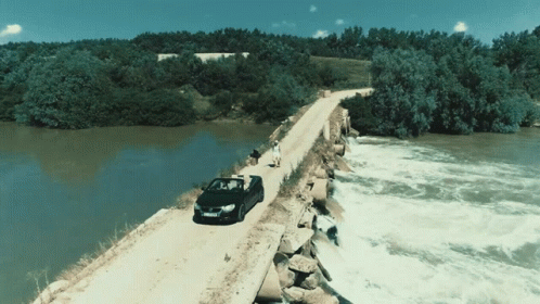 the car is driving on the bridge over the water