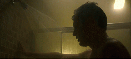 a man in the shower looking at a light